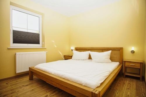 ein Schlafzimmer mit einem Bett mit weißen Laken und einem Fenster in der Unterkunft Schicke FeWo mit Terrasse, gratis Nutzung vom AHOI Erlebnisbad und Sauna in Sellin - Haus De niege Wech FeWo 01 in Thiessow