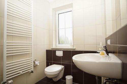 ein weißes Badezimmer mit Waschbecken und Toilette in der Unterkunft Schicke FeWo mit Terrasse, gratis Nutzung vom AHOI Erlebnisbad und Sauna in Sellin - Haus De niege Wech FeWo 01 in Thiessow