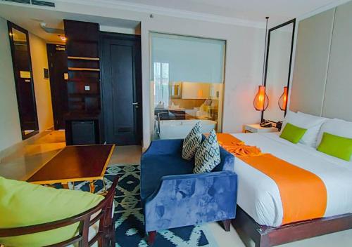 a hotel room with a large bed and a dining room at Jambuluwuk Oceano Seminyak Hotel in Seminyak