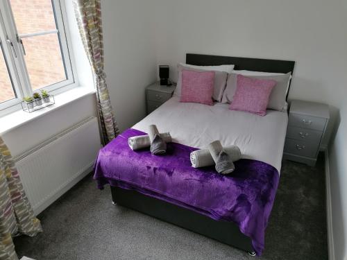 a bedroom with a large bed with purple sheets and pillows at Agnes House in Grimsby