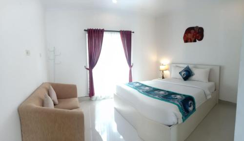 a bedroom with a bed and a chair and a window at Gaing Mas Residence By Gaing Mas Group in Jimbaran