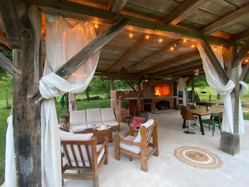 un patio couvert avec des chaises, une table et une cheminée dans l'établissement Cinija Cottage - Family Eco Retreat in Nature Park, à Kupčina