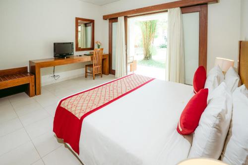 a bedroom with a bed with red pillows and a desk at Pertiwi Resort & Spa in Ubud