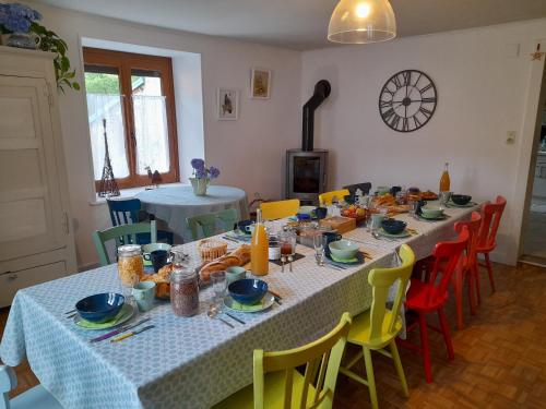 un comedor con una mesa con sillas amarillas y azules en La maison du vannier en Raon-lès-Leau