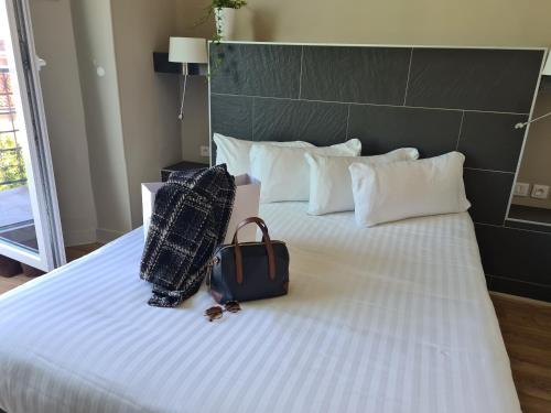 a bed with two bags and a suitcase on it at Hôtel Amirauté in Toulon
