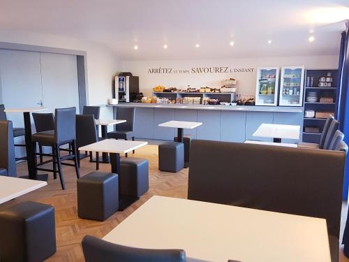 a restaurant with tables and chairs and a counter at Kyriad Hôtel La Fleche in La Flèche