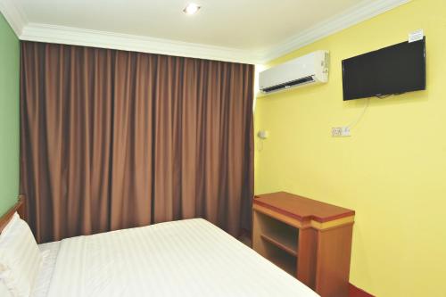 a bedroom with a bed and a desk and a television at Mandarin Inn in Mukah