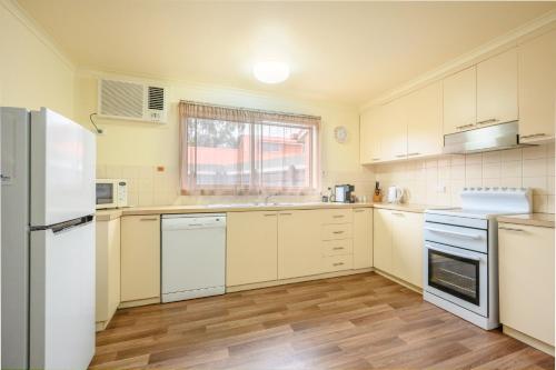 a kitchen with white cabinets and a white refrigerator at AAt 28 Goldsmith Motel in Hamilton