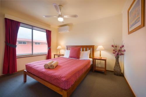 a bedroom with a bed with a pink blanket and a window at AAt 28 Goldsmith Motel in Hamilton