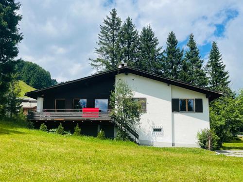 a small white house with a red bench in a field at La Civetta (714 La) in Valbella