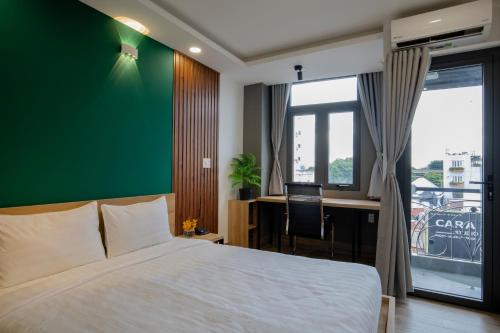 Un dormitorio con una cama y un escritorio y una pared verde. en LÁ HOTEL RIVERSIDE, en Ho Chi Minh