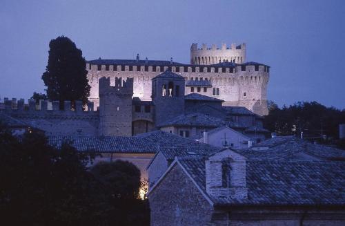 a large castle is lit up at night at La Pulcia B&B in Gradara