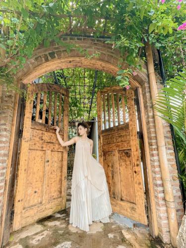 a woman in a white dress standing in front of a gate at Mai Chau Rustic Home in Mai Chau