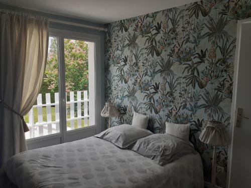 une chambre avec un lit avec un papier peint fleuri dans l'établissement Les Varennes, à Saint-Alban-les-Eaux