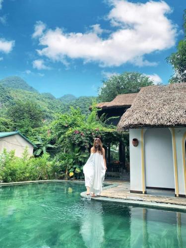 a woman standing next to a swimming pool at Mai Chau Rustic Home in Mai Chau