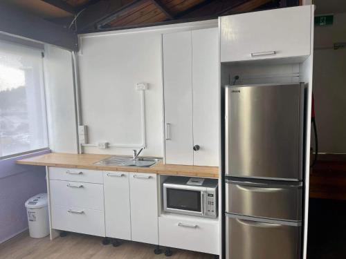 a kitchen with white cabinets and a stainless steel refrigerator at Kamo Studio Apartment in Whangarei