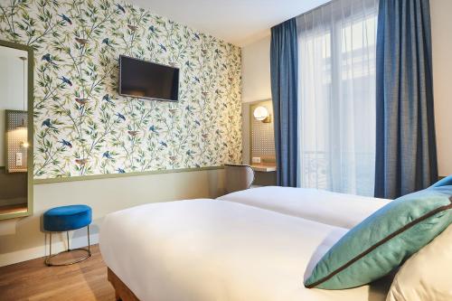 a hotel room with a bed and a tv at Hotel Cervantes by Happyculture in Paris