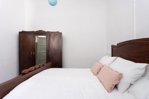 a bedroom with a wooden bed with white sheets and pink pillows at Home2Book Arafo Rural Escape BBQ in Arafo