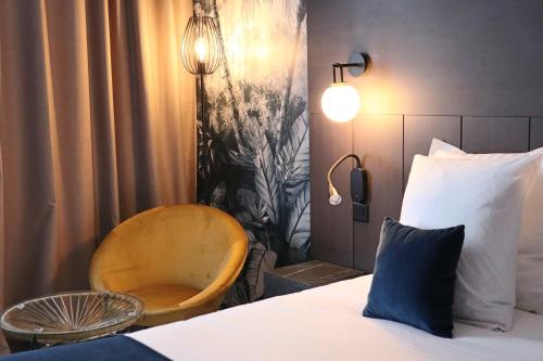 a bedroom with a bed with a chair and a lamp at Quintessia in Orvault
