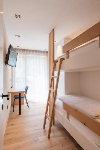 a bedroom with a bunk bed with a desk and a desk at VANEA - Alp Relax Guesthouse in Chienes