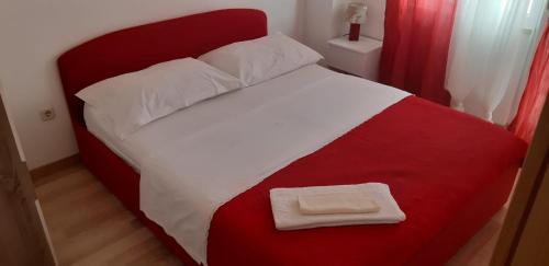 ein rotes und weißes Bett mit einer roten und weißen Decke in der Unterkunft Apartments Luka in Sevid