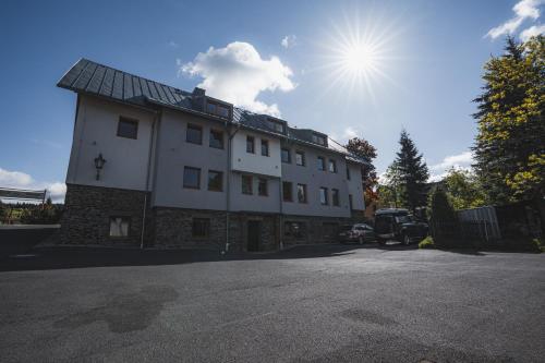 a large white building with the sun in the sky at Apartmány Jurica Boží Dar 84 in Boží Dar