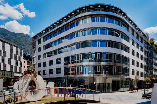un gran edificio de oficinas con una escultura delante en Hotel Starc by Pierre & Vacances Premium en Andorra la Vella
