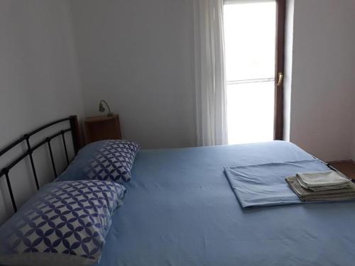 a bed with a blue comforter and a window at Basil Apartments and Rooms in Betina
