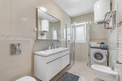 bagno bianco con lavandino e lavatrice di Apartment Mariuccia with Private Pool a Vrsar