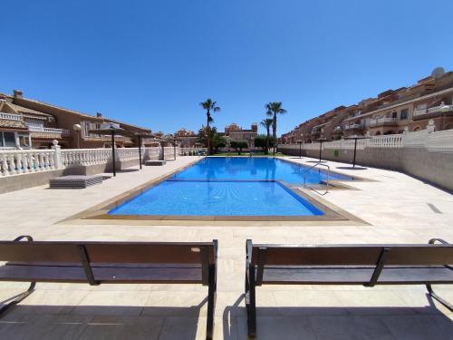 een zwembad met twee banken ervoor bij La Casa de Gonzalo in Gran Alacant