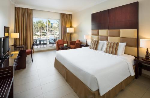 a hotel room with a large bed and a television at Millennium Central Al Mafraq in Abu Dhabi