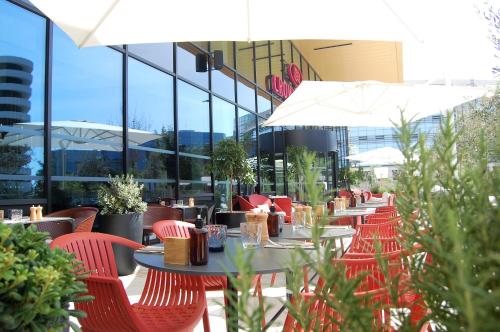 a restaurant with red chairs and tables and umbrellas at Crowne Plaza - Nice - Grand Arenas by IHG in Nice