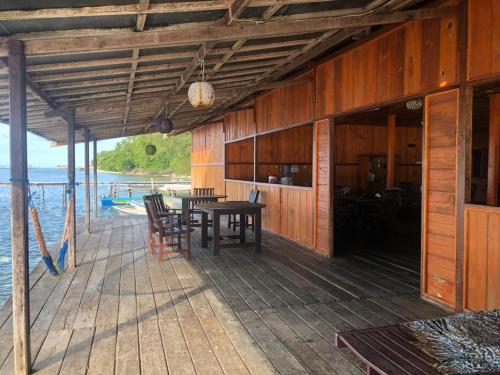a wooden deck with a table and chairs on the water at Yenkoranu Homestay and Dive Center in Waisai
