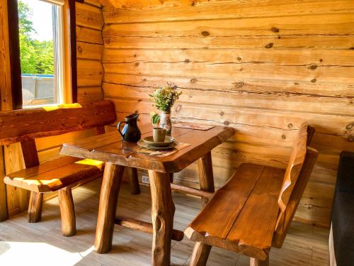 een houten tafel en bank in een kamer met een houten muur bij Domki Kaktus in Osieki