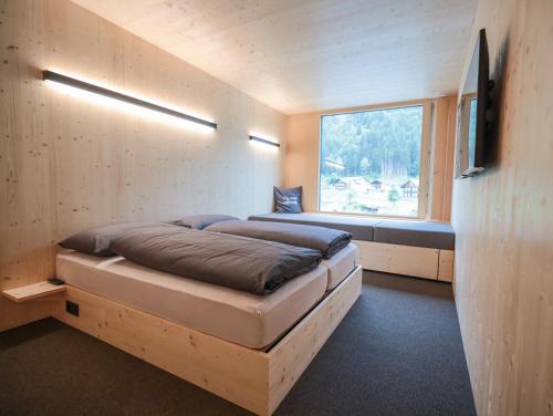 a small bedroom with a bed and a window at Revier Mountain Lodge Montafon in Sankt Gallenkirch