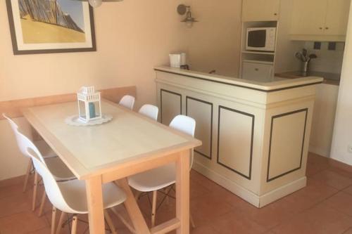 cocina con mesa de madera y sillas blancas en Maison de 2 chambres avec piscine partagee terrasse amenagee et wifi a Lacanau a 2 km de la plage, en Lacanau