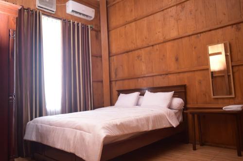 1 dormitorio con 1 cama con pared de madera en Omah Kayu Villa en Pasirputih
