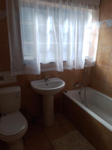 a bathroom with a toilet and a sink and a tub at Anna Boeremeisie Guesthouse in Benoni