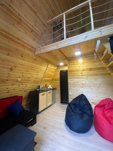 a room with wooden walls and a loft with red and blue chairs at Labna Huts in Mestia