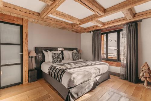 um quarto com uma cama grande e janelas em Les Suites – Maison Bouvier em Tignes