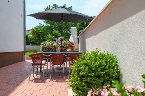 a table with chairs and an umbrella on a patio at Apartments SoMi in Poreč