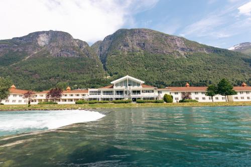 un resort sull'acqua con montagne sullo sfondo di Hotel Loenfjord Loen a Loen
