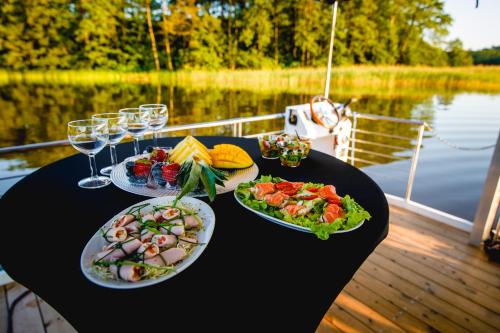 un tavolo con piatti di cibo e bicchieri da vino su una barca di Houseboat- dom na wodzie z sauną i możliwością pływania a Iława