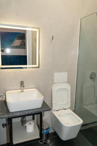 a bathroom with a sink and a toilet and a mirror at Hilltop Heaven Hotel in Sarandë