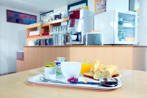 a plate of food with bread and orange juice on a table at Premiere Classe Evreux in Évreux