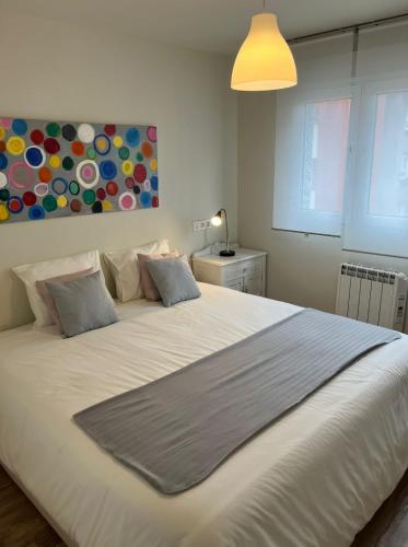 1 cama blanca grande en un dormitorio con lámpara en Precioso piso soleado totalmente reformado en Gijón, en Gijón