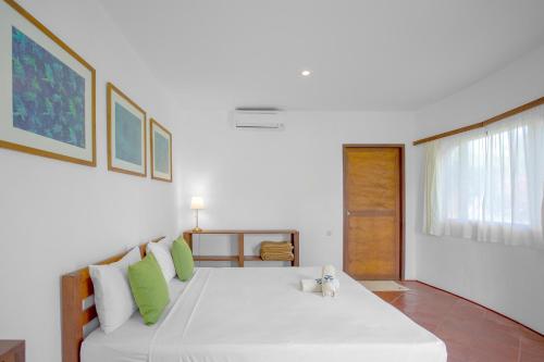 a bedroom with a large white bed with green pillows at Whales and Waves in Lemonga