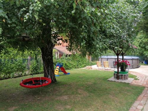 a yard with a tree and a playground with a tree at Vila Mila Fruška Gora in Velika Remeta