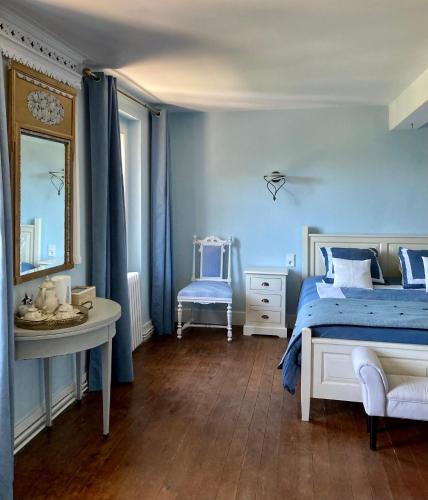 - une chambre bleue avec un lit et un miroir dans l'établissement Domaine de Ménerque - petit château avec piscine, à Lisle-sur-Tarn