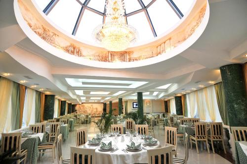 een feestzaal met witte tafels en stoelen en een kroonluchter bij Park Hotel Stavropol in Stavropol